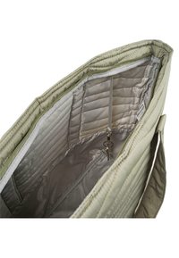 Interior de bolsa acolchada verde claro con textura acolchada, que presenta un bolsillo con cremallera y un llavero, forrado con una suave tela gris claro.