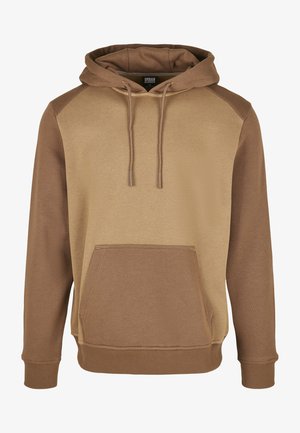 Hnedá mikina s kapucňou a svetlejším béžovým predným dielom a tmavšími hnedými raglánovými rukávmi. Obsahuje prednú vrecko na ruky a nastaviteľnú kapucňu so šnúrkou.