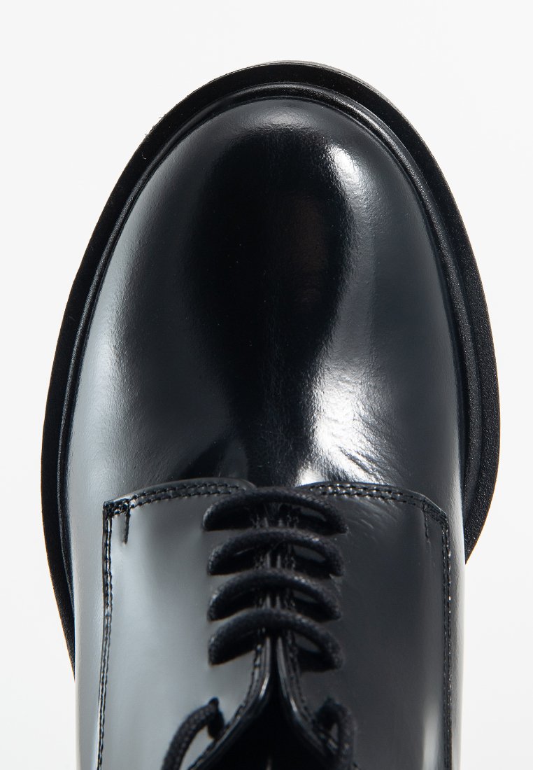 Chaussure habillée en cuir noir avec une finition brillante, dotée d'un bout arrondi, de lacets texturés et d'une silhouette épurée. Design minimaliste.