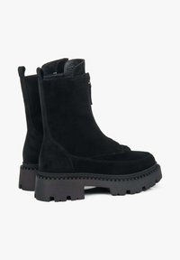 Zwarte suède enkellaarzen met een robuuste rubberen zool, gestructureerde details en een ritssluiting aan de zijkant. Voorzien van trekflappen voor gemakkelijk aan- en uittrekken.