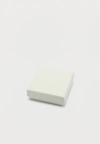 Μικρό κλειστό λευκό τετράγωνο κουτί δώρου με διακριτική υφή σε απλό λευκό φόντο.