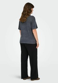 Szary sweter z krótkimi rękawami i okrągłym dekoltem, w połączeniu z czarnymi spodniami w szerokiej nogawce. Materiał wydaje się miękki i ma teksturowany wygląd.