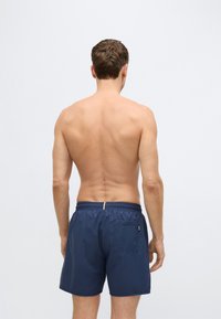 Férfi sötétkék úszónadrág elasztikus derékpánttal, hátsó zsebbel és könnyű anyagból. Simább textúra és egyszerű kialakítás.