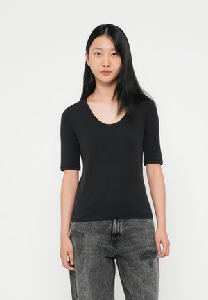 Svart ribbet t-skjorte med kort erm og rund hals, glatt tekstur, tettsittende design, kombinert med grå teksturerte jeans.