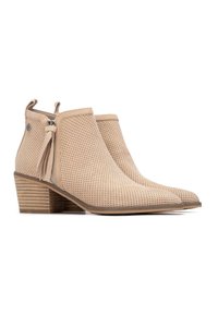 Botines beige perforados con cremallera lateral, adorno de borlas y tacón de madera apilada, con un diseño elegante de punta afilada.