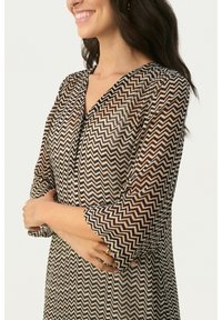 Robe translucide marron et crème avec un motif en zigzag, décolleté en V et manches trois quarts, présentant une coupe ample et un tissu texturé.