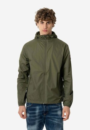 Veste légère vert olive avec capuche, fermeture éclair frontale et poignets élastiques. Dotée de deux poches latérales et d'un logo brodé sur la manche.