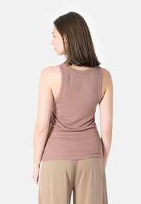 Brown ribbed tank top with a fitted design, featuring a scoop neckline and a smooth texture, paired with loose beige pants.