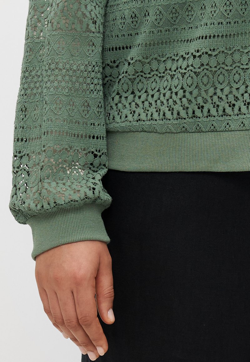 Jasnozielony, koronkowy sweter z teksturowymi wzorami; ściągacze na rękawach; z misternymi wzorami i otwartymi sekcjami dzianiny.