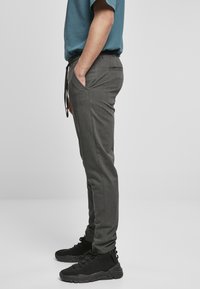Joggers ajustados en gris carbón con cinturilla elástica y cordón ajustable. Presenta bolsillos laterales y una tela sutilmente texturizada.