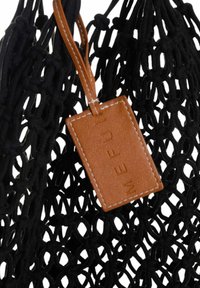 Borsa a rete nera con una forma strutturata, caratterizzata da un'etichetta in pelle marrone con testo in rilievo. Tessuto testurizzato con nodi visibili.