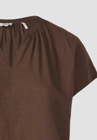 Bruine blouse met korte mouwen en een V-hals, met geplooide details bij de schouders en een lichtgewicht, gestructureerde stof.