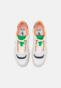 Vita sneakers med marinblå accenter, orange snören och gr öna detaljer. Har perforerat tåkappa och vadderad krage för komfort.