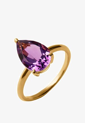 Anillo de oro con una gran piedra preciosa morada en forma de pera asegurada por tres garras sobre una banda lisa y sencilla sobre un fondo blanco.