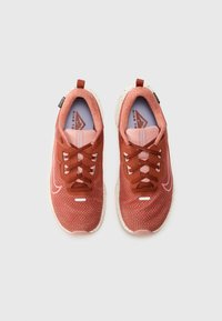 Nike sneakers met een gestructureerde rood-oranje stof bovenkant, contrasterende roze accenten, ronde veters en een gevlekte witte tussenzool.