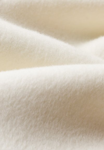Weicher, weißer Stoff mit glatter, plüschiger Textur; leicht flauschige Oberfläche mit sanften, fließenden Falten, die Flexibilität und Wärme anzeigen.