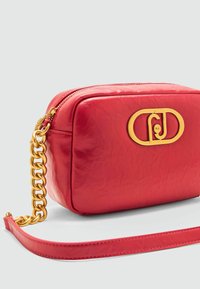 Rote Kunstleder-Crossbody-Tasche mit Gold-Logo, weicher Textur, Reißverschluss und Kettenriemen. Kompakte rechteckige Form mit detaillierten Akzenten.
