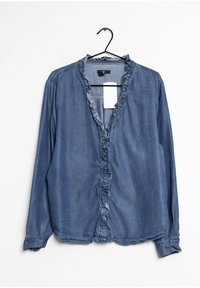 Blouse en denim bleu foncé avec un col à volants, des manches longues et une fermeture à boutons sur le devant. Texture lisse et design décontracté.
