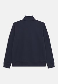 Jersey azul marino con cuello alto y mangas largas, que presenta una textura suave y puños elásticos en el dobladillo.