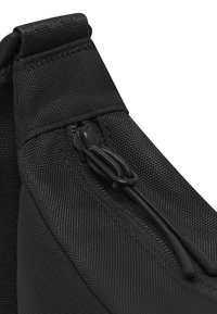 Borsa in tessuto nero con una superficie testurizzata, dotata di chiusura con zip e corde nere per un'apertura facile. Design compatto e angolare.
