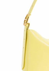 Borsa a tracolla in pelle gialla con una superficie liscia, dotata di una fibbia color oro su una tracolla regolabile e una forma slanciata e curva.
