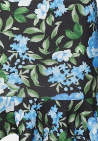 Tecido floral com fundo preto apresentando flores azuis e folhas verdes. O design inclui formas variadas de flores e uma bainha franzida.