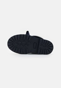 Semelle en caoutchouc noir avec un motif de relief distinct, dotée de rainures de traction et d'une zone de orteil renforcée. Design de bord supérieur lisse pour un confort accru.