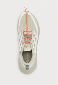 Light grey athletic shoe with white accents and orange laces, featuring a textured upper and a padded collar for comfort.