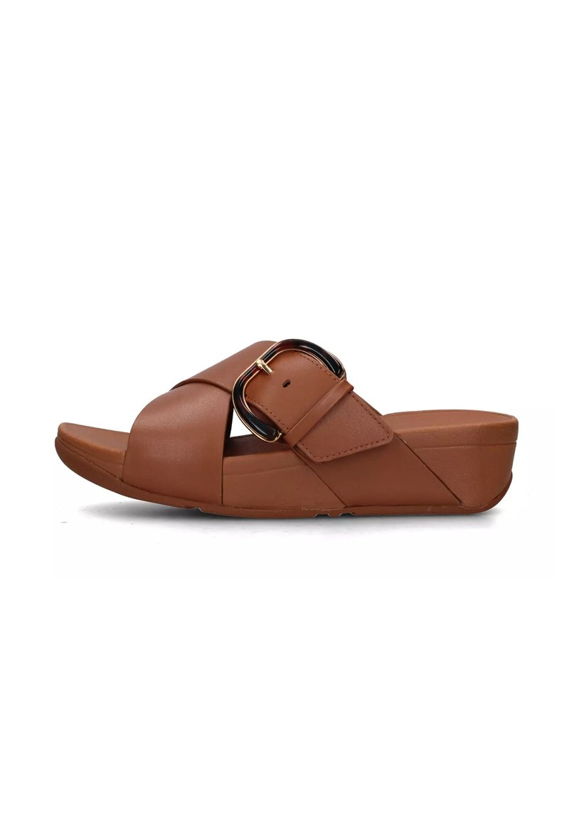 Sandal in pelle sintetica di colore marrone. Presenta cinturini incrociati e una fibbia decorativa dorata. Suola a zeppa bassa per maggiore comfort.