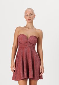 Punane sädelev seotud kleit, millel on südamekujuline kaelus, keha lähedane lõige ja laienev seelik, mille esiosal on peened voldid.