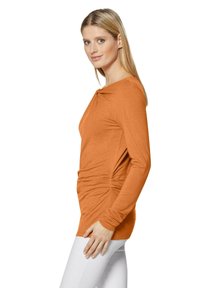 Langärmliges Oberteil in verbranntem Orange, aus weichem Stoff gefertigt, mit einem geknoteten Detail am Halsausschnitt und gerafften Seiten für eine figurschmeichelnde Silhouette.