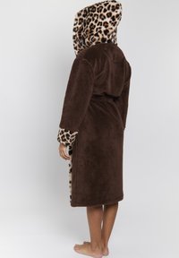 Bata de baño marrón, esponjosa, con capucha y puños de estampado de leopardo, que cuenta con un cinturón en la cintura y un diseño hasta las rodillas. Textura suave y material acolchado.