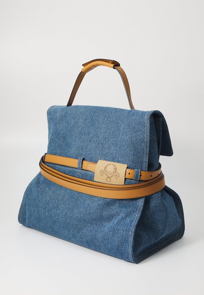 Denim handbag with a structured shape, brown leather handle and accent belt. Features a logo patch and top flap closure.