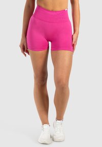 Roze sportsshorts met hoge taille, voorzien van een geribbelde tailleband en een gladde textuur, gecombineerd met witte sportschoenen.