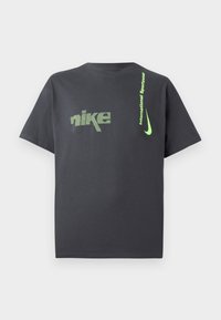 Mørkegrå bomulds-t-shirt med et grønt pixeliseret "nike" logo og tekst, samt en iøjnefaldende grøn swoosh detaljer på siden.