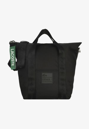 Černá taška Lacoste s dvojitými uchy, zipovým uzávěrem a zeleným ramenním popruhem s bílým logem Lacoste.