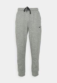 Grå Nike sweatpants med dragsko i midjan, avsmalnande ben och en liten svart logotyp på vänster lår. Tillverkade av ett strukturerat, mjukt material.