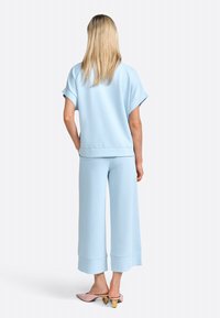 Completo loungewear due pezzi blu chiaro con top a maniche corte e pantaloni a gamba larga. Tessuto morbido, cuciture minimal e vestibilità rilassata.