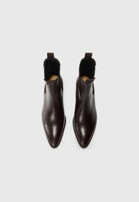 Bottes chevilles en cuir bordeaux avec un bout pointu, texture lisse, panneaux latéraux élastiques et une languette au talon pour un enfilage facile.