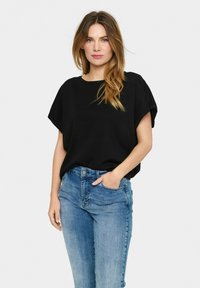 Sort, løstsiddende t-shirt med korte ærmer, parret med lyseblå, høj talje jeans. Glat tekstur og enkelt design.