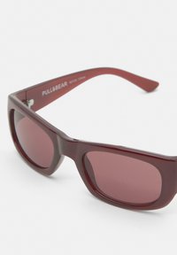 Occhiali da sole rettangolari bordeaux con lenti fumé e montatura spessa, marchiati "PULL&BEAR" all'interno dell'asta.