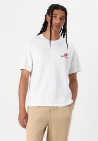 Witte katoenen t-shirt met een kleine kleurrijke aardbeienafbeelding en het woord "Aardbei" in zwarte tekst. Casual, ontspannen pasvorm ontwerp.
