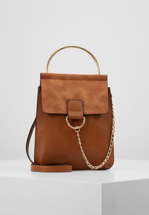 Braune Leder- und Wildlederhandtasche mit goldenem Metallgriff, goldenem Kettendetail und abnehmbarem Schulterriemen auf weißer Oberfläche.