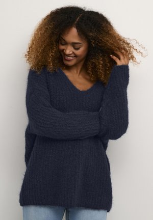 Marineblauer, locker gestrickter Pullover mit V-Ausschnitt, langen Ärmeln und textiler Oberfläche. Lässiger, oversized Schnitt mit seitlichen Schlitzen für optimale Bewegungsfreiheit.