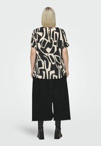 Short-sleeve top in cream with black abstract patterns, paired with wide black cropped pants. The outfit features a back keyhole detail.