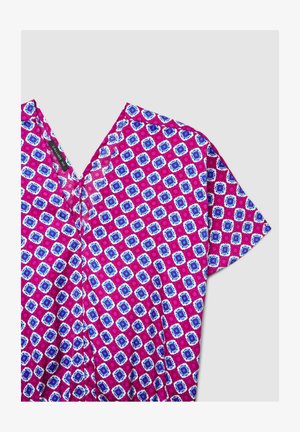 Blouse à manches courtes avec motif floral circulaire vibrant en rose, bleu et blanc et col en V sur fond gris.
