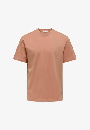 T-shirt a maniche corte, con collo rotondo, in morbido cotone rosa pesco. Presenta una linea dritta e un piccolo etichetta laterale per il branding.