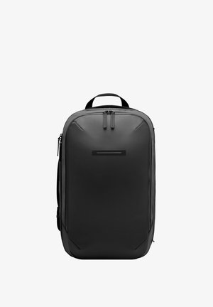 Un sac à dos noir en matériau durable avec une forme rectangulaire élégante, doté de deux zips, d'une poignée supérieure et d'un accent frontal minimaliste.