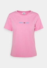Růžové bavlněné tričko s krátkým rukávem, na kterém je modrý nápis "TOMMY" a malý červenobílý design loga uprostřed. Kulatý výstřih.