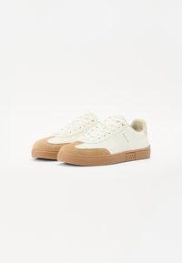 Sneaker bianche con dettagli in suede beige, design con lacci, dettagli perforati sui lati e suola in gomma. Logo impresso sul lato.